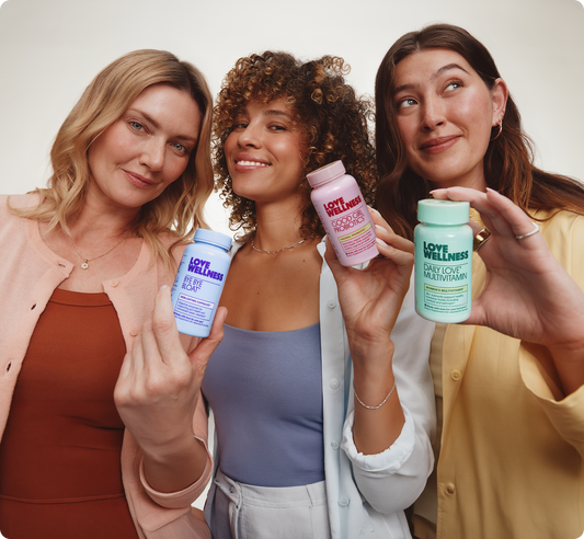 Three smiling women holding Love Wellness probiotic supplements