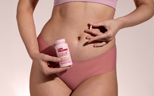 Woman holding Love Wellness Good Girl Probiotics with a capsule in hand