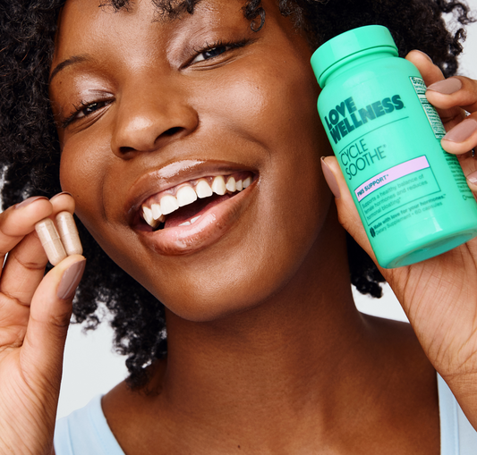 Smiling woman holding Love Wellness Cycle Soothe capsules, a supplement for cycle support