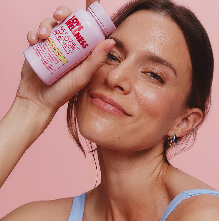 Smiling woman holding Love Wellness Good Girl Probiotics, a vaginal probiotic for odor and pH support