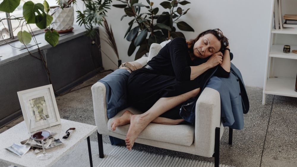 Tired woman asleep in an armchair in a bright living room