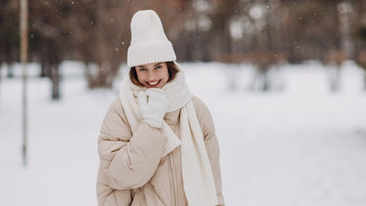 Smiling woman in a white winter hat and scarf outdoors in the snow